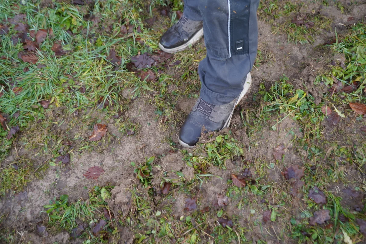 Ein Schuh steht im Dreck und zeigt auf Furchen.